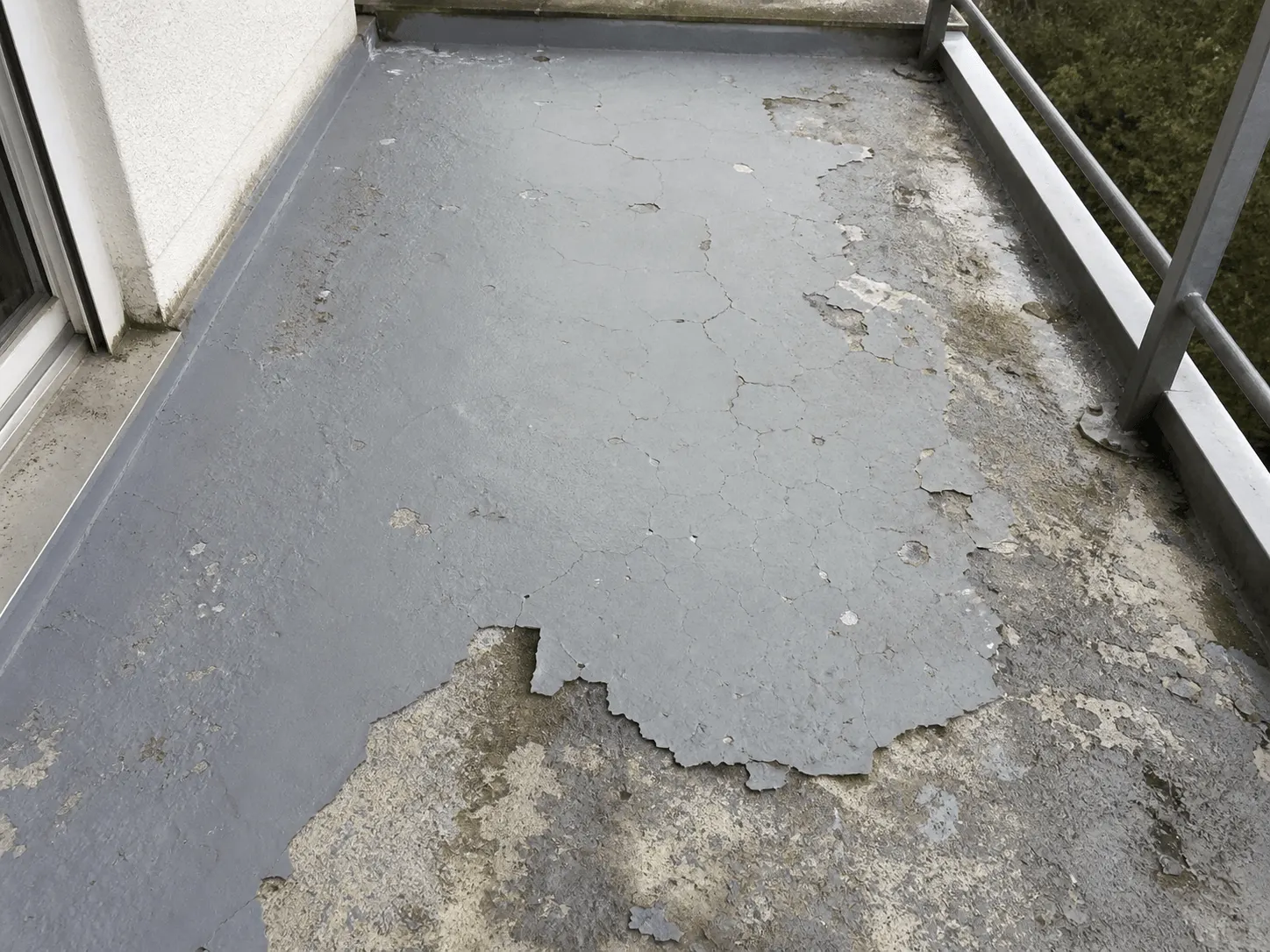 Feuchte Kellerwand mit sichtbaren Wasserschäden und Schimmelbildung nahe einem kleinen Fenster.