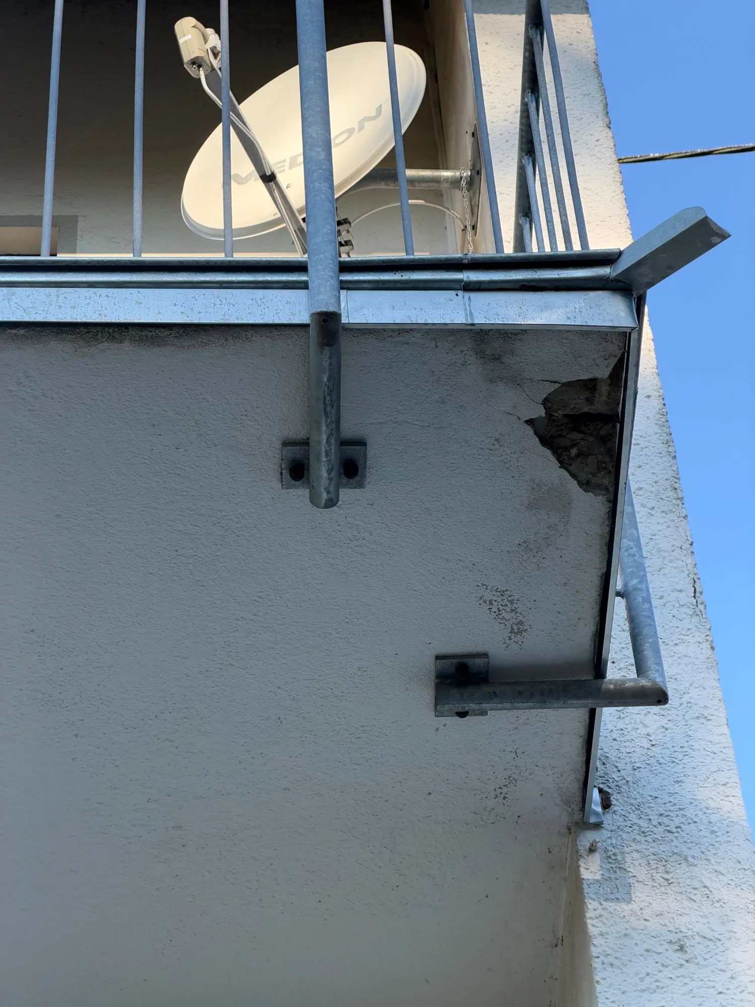 Abplatzung an der Balkonplatte neben der Geländerbefestigung