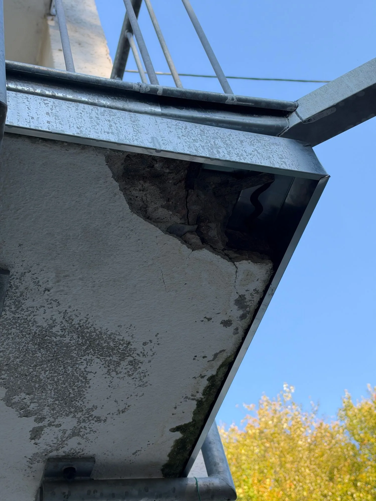 Abgeplatzte Betonecke unter dem Randprofil einer Balkonplatte