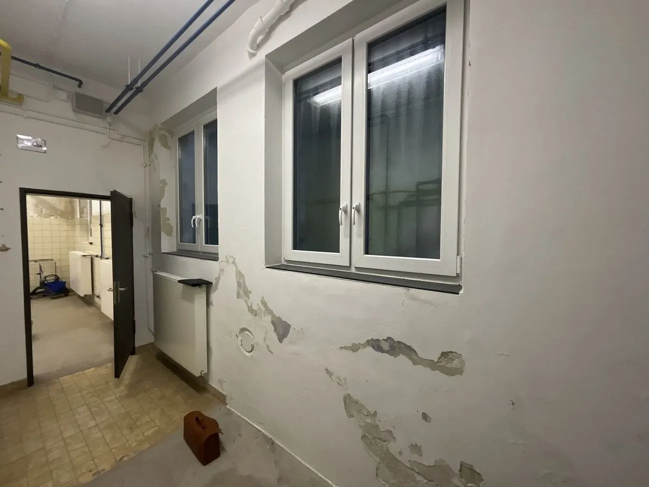 Flurwand mit abgeplatztem Putz neben einer offenen Tür