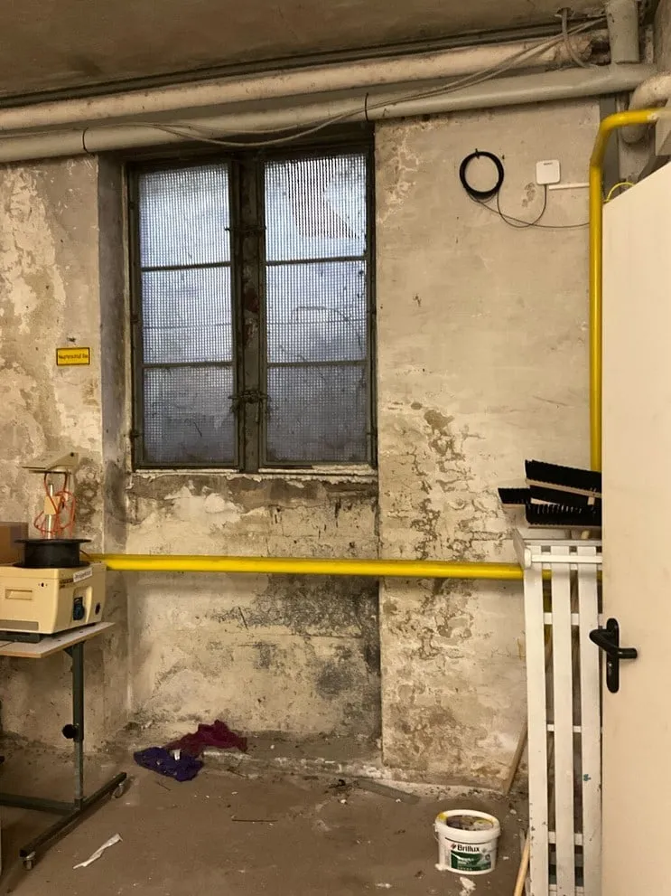 Kellerwand unter einem Fenster mit abgeplatztem Putz